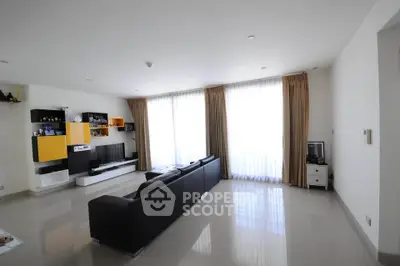 Spacious modern living room with sleek black sofa and large windows for natural light.