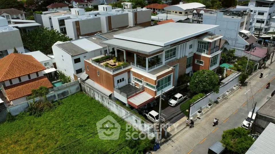 Modern multi-story building with rooftop terrace and lush surroundings in urban neighborhood.