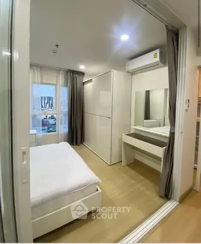 Modern bedroom with sleek design, featuring a large mirror and ample natural light.