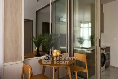 Modern kitchen with wooden dining set and washing machine, featuring sleek glass partitions.