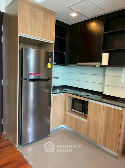 Modern kitchen with sleek appliances and wooden cabinetry in a stylish apartment.