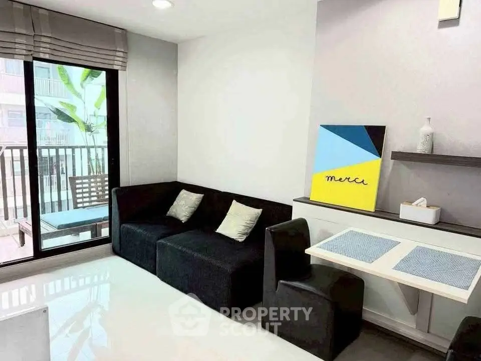 Modern living room with sleek black furniture and balcony access in a stylish apartment.