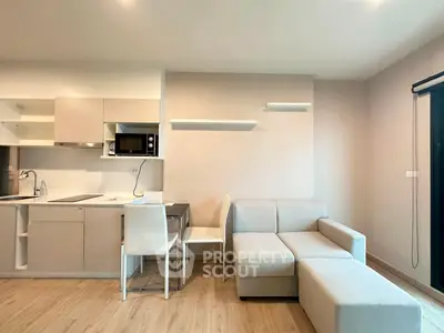 Modern open-layout kitchen and living room with sleek furniture and neutral tones.