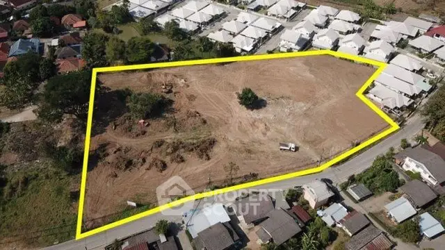 Aerial view of a large plot of land outlined in yellow, surrounded by residential houses.