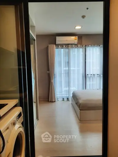 Modern bedroom with large windows and washing machine in view, offering a bright and functional living space.