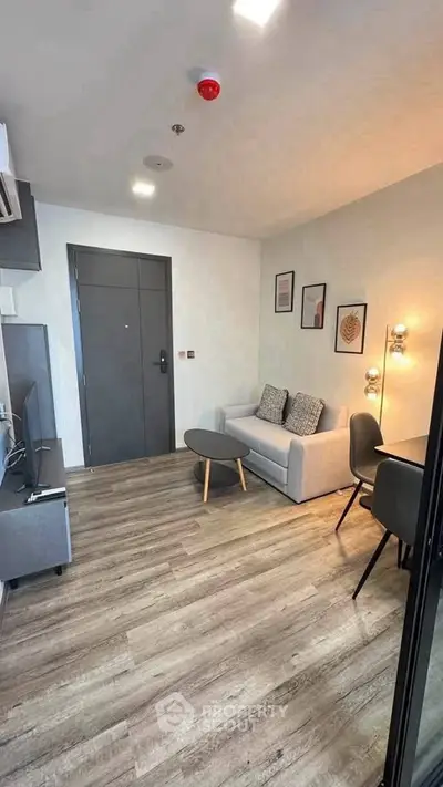 Modern living room with stylish decor and wooden flooring, featuring a cozy sofa and wall art.