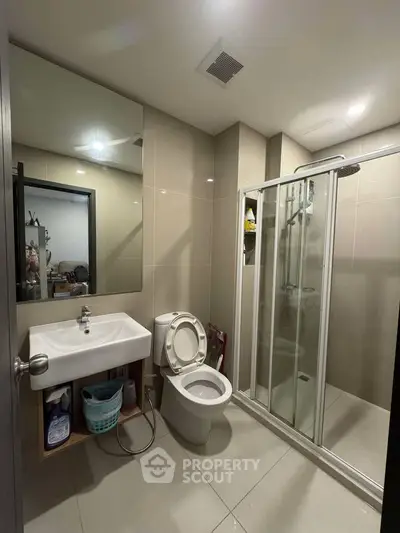 Modern bathroom with glass shower and sleek fixtures in contemporary apartment.