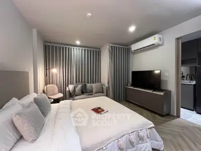 Modern bedroom with cozy seating area and sleek TV setup, featuring stylish decor and ambient lighting.