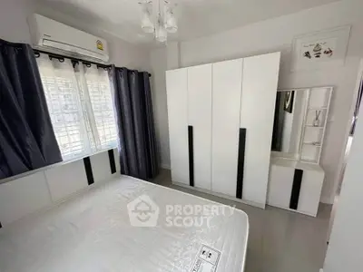 Modern bedroom with sleek white wardrobe and air conditioning, perfect for comfort and style.