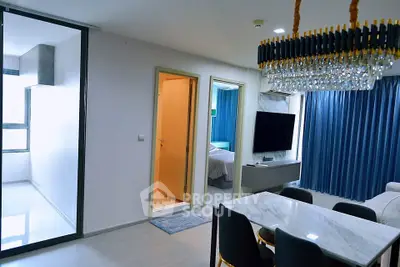 Modern open-plan living and dining area with elegant chandelier and marble table.