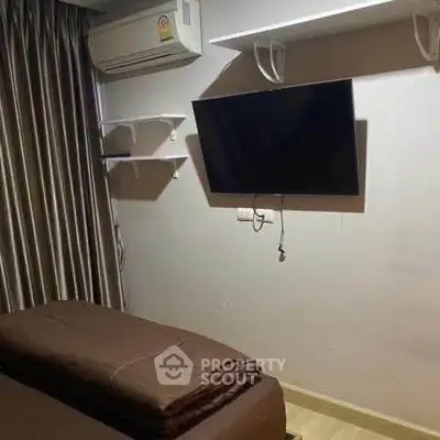 Cozy bedroom with wall-mounted TV and air conditioning unit, perfect for relaxation.