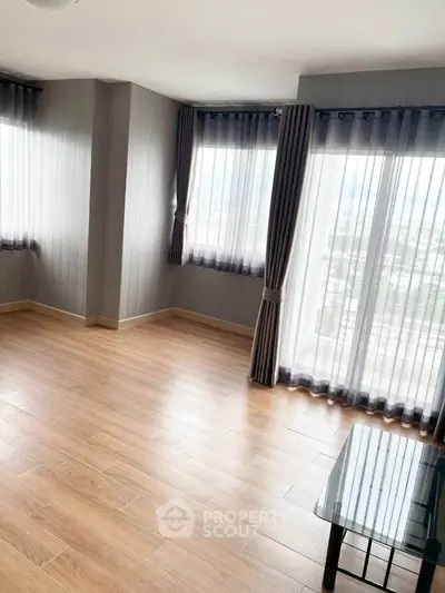 Spacious corner unit with large windows and elegant wood flooring, offering abundant natural light and city views.