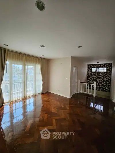 Spacious living room with elegant wooden flooring and large windows for natural light.