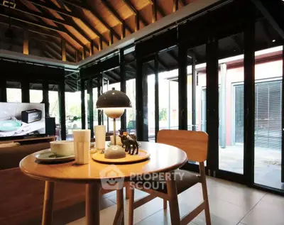 Charming living room with modern decor and large windows offering natural light and outdoor views.