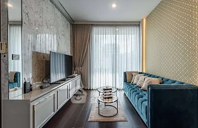 Stylish modern living room with elegant decor and large TV, featuring a plush blue sofa and floor-to-ceiling windows.