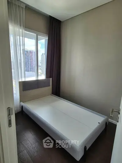Cozy bedroom with modern bed frame and large window offering city view