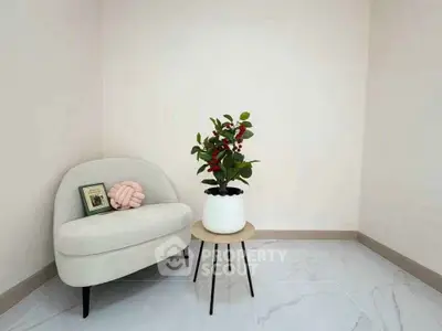 Minimalist living room with modern chair and potted plant on sleek tiled floor.