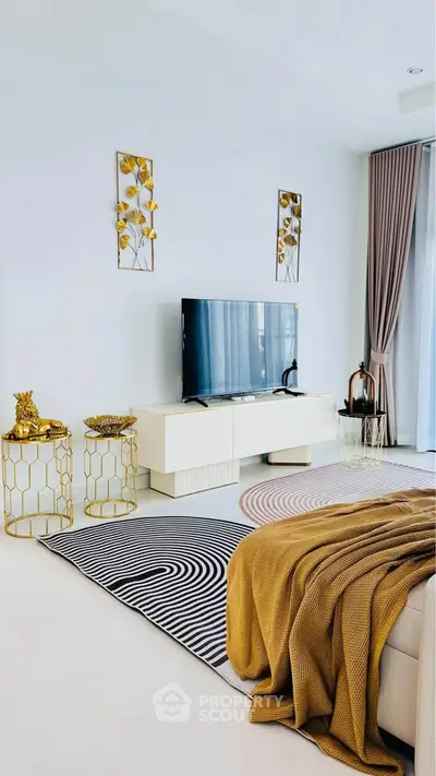 Modern living room with stylish decor and large TV, featuring elegant gold accents and cozy ambiance.