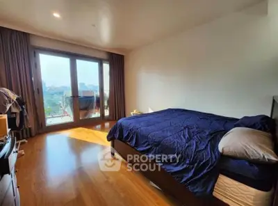 Spacious bedroom with large windows and wooden flooring, offering ample natural light and a cozy atmosphere.