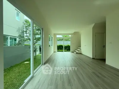 Spacious modern living room with large windows and garden view, perfect for natural light lovers.