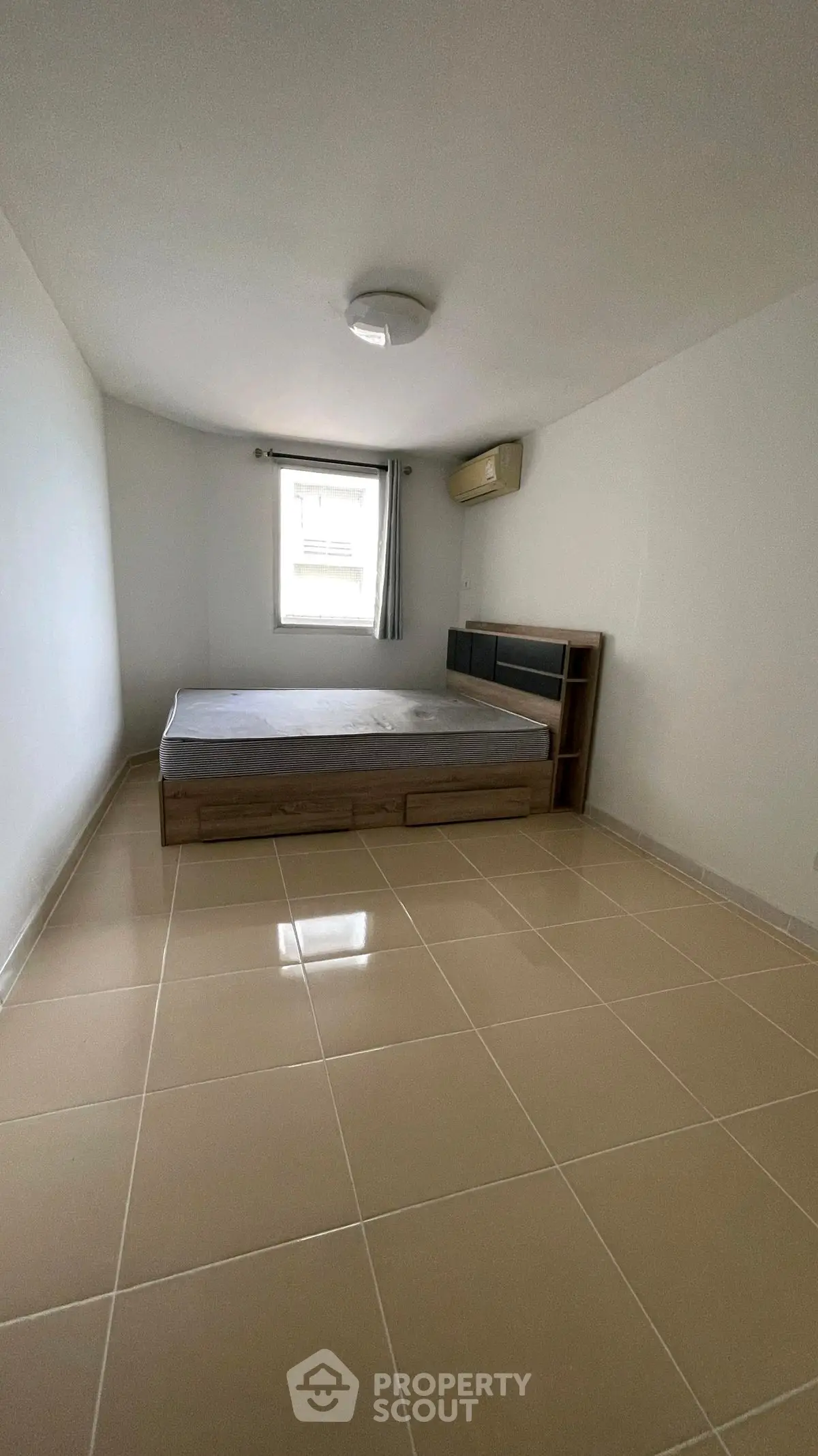 Spacious bedroom with minimalist design and large window for natural light.