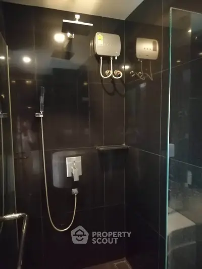 Modern bathroom with sleek black tiles and advanced shower system