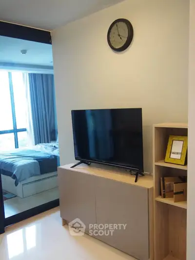 Modern apartment interior with TV and bedroom view, sleek design and natural light.