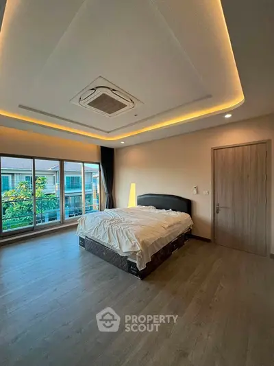 Spacious bedroom with modern ceiling design and large windows offering natural light.