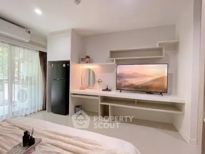 Modern bedroom with sleek built-in storage and large TV, featuring natural light and stylish decor.