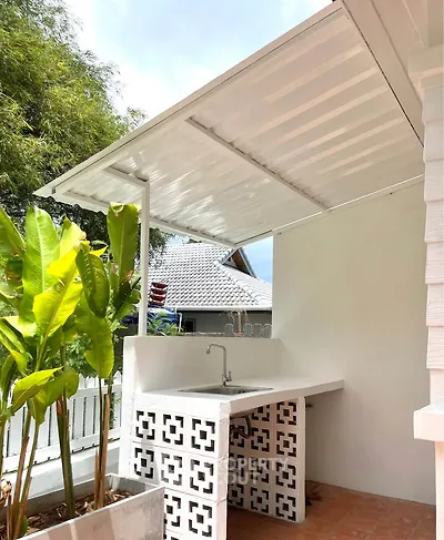 Charming outdoor kitchen with modern sink and stylish design, perfect for entertaining in a cozy backyard.