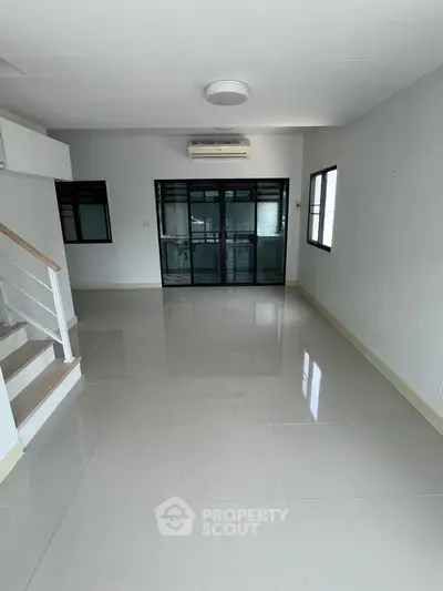 Spacious modern living room with sleek tile flooring and large windows for natural light.