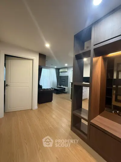 Modern apartment interior with open layout and wooden flooring, featuring a cozy living area and stylish shelving.
