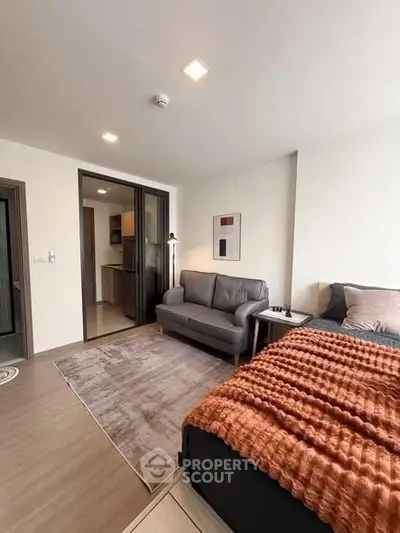 Modern studio apartment with cozy bed and stylish sofa in open layout.