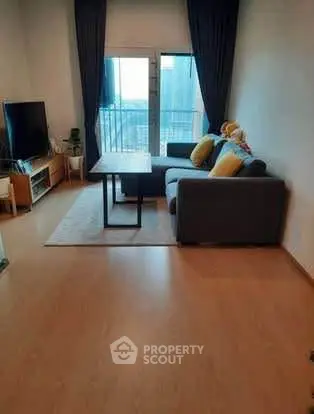Cozy living room with modern sofa and TV, featuring a small balcony view.