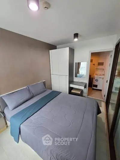 Modern bedroom with sleek design and adjacent laundry area, featuring a cozy bed and ample storage.