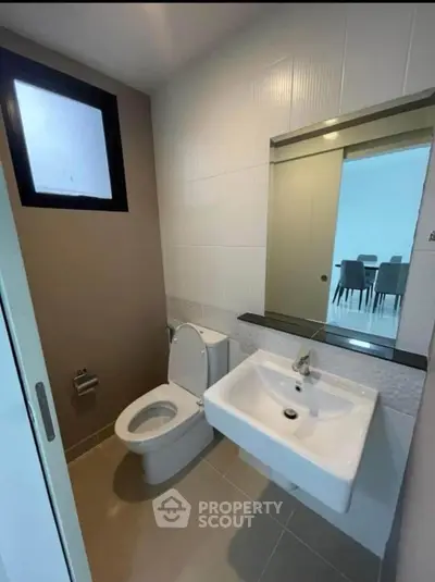 Modern bathroom with sleek fixtures and a large mirror, adjacent to a dining area.