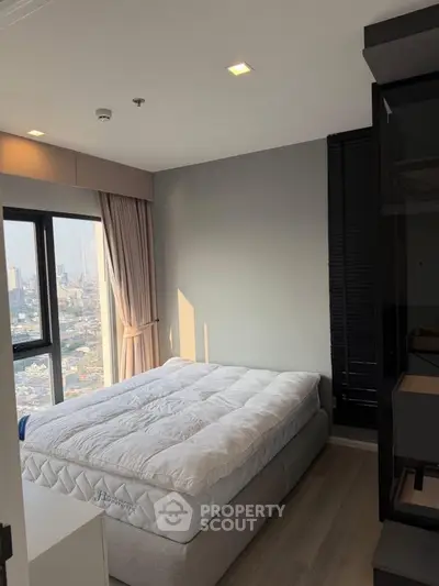 Modern bedroom with city view and natural light, featuring a comfortable bed and stylish decor.