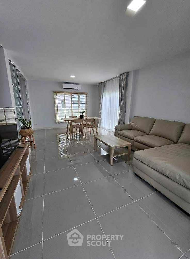 Spacious modern living room with sleek tile flooring and cozy seating area.