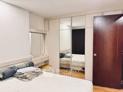 Cozy bedroom with mirrored wardrobe and wooden flooring