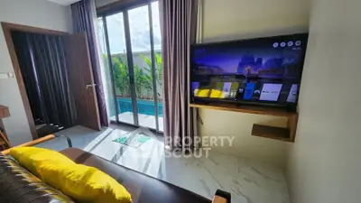 Modern living room with pool view, featuring sleek TV setup and stylish decor.