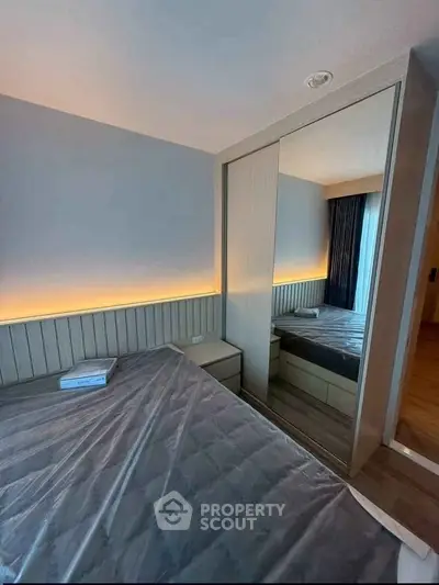 Modern bedroom with stylish lighting and mirrored wardrobe in a cozy apartment.