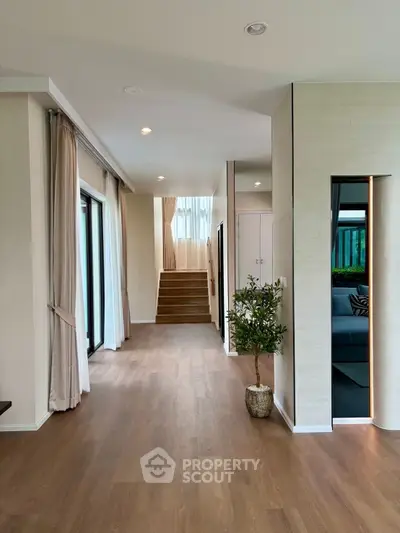 Spacious modern living area with wooden flooring and large windows for natural light.