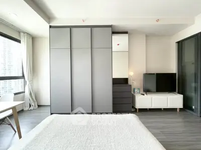 Modern bedroom with sleek wardrobe and large windows in a high-rise apartment.