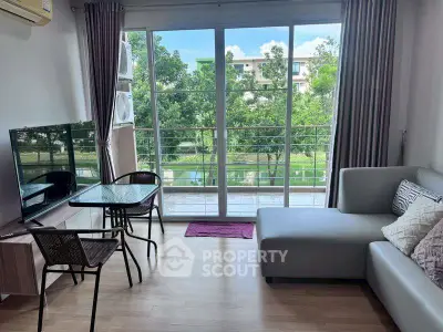 Modern living room with large windows and balcony view, featuring sleek furniture and natural light.