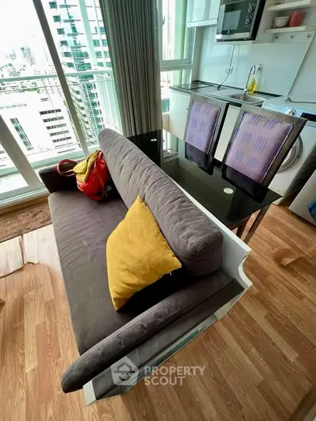 Modern living room with city view, featuring a cozy sofa and sleek kitchen area.