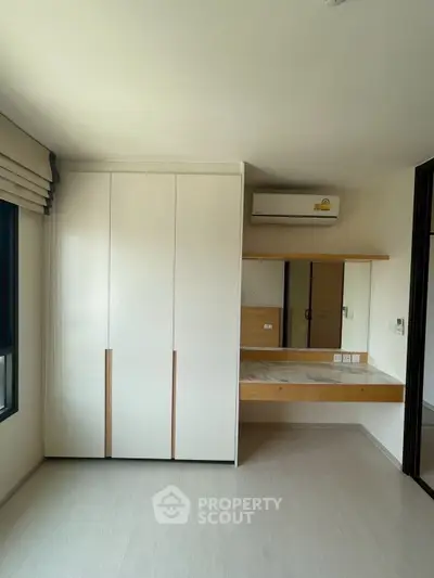 Modern bedroom with built-in wardrobe and air conditioning in a bright, minimalist design.