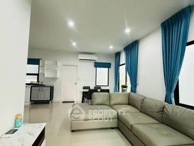 Modern living room with open kitchen, featuring sleek furniture and bright natural light.
