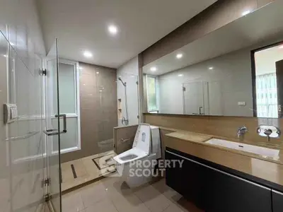 Spacious modern bathroom with glass shower and sleek vanity in luxury apartment.