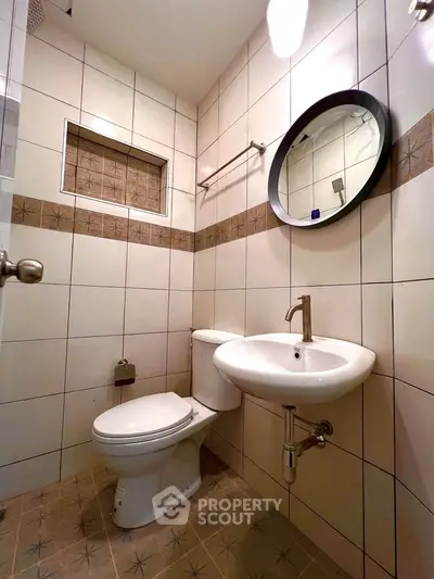 Modern bathroom with stylish round mirror and elegant fixtures in a tiled setting.
