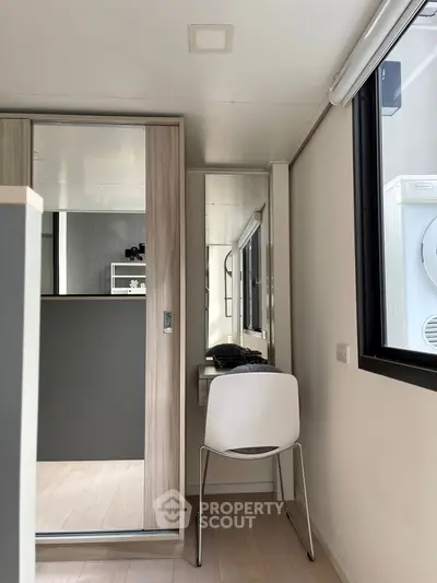 Modern compact study nook with sleek chair and mirrored closet in bright apartment.